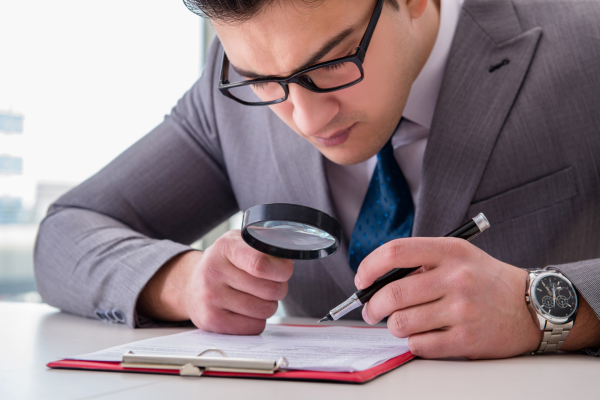 Magnifying glass over fine print on an insurance document, illustrating critical business insurance mistakes in Malaysia.